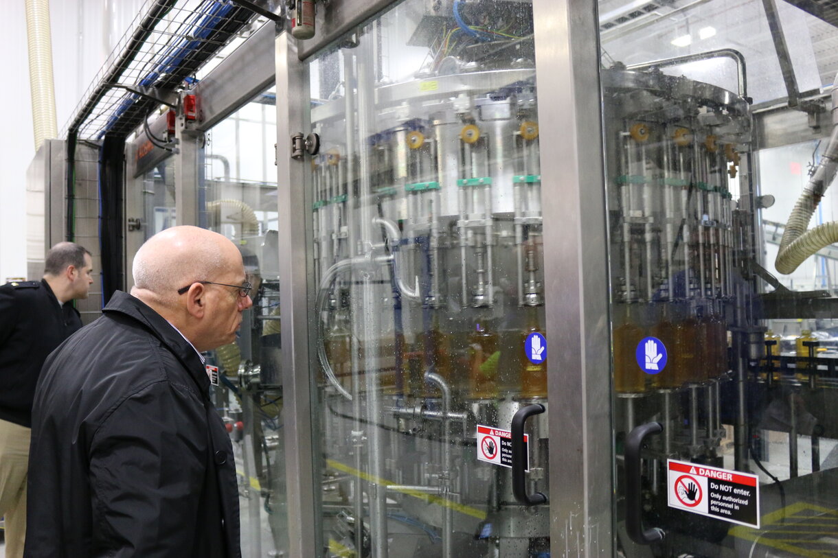 Inspector examining a stainless steel filling machine on a food production line