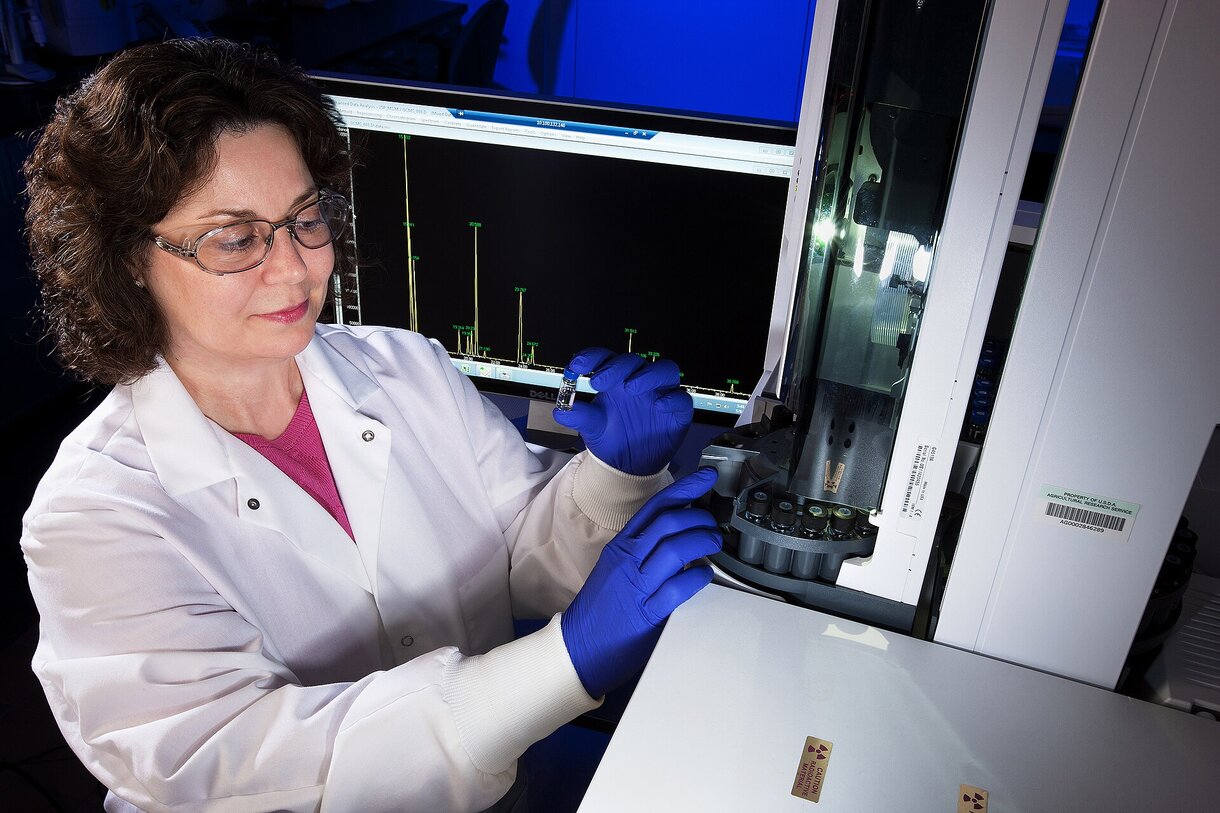 Laboratory technician operating a gas chromatograph with a chromatogram on screen